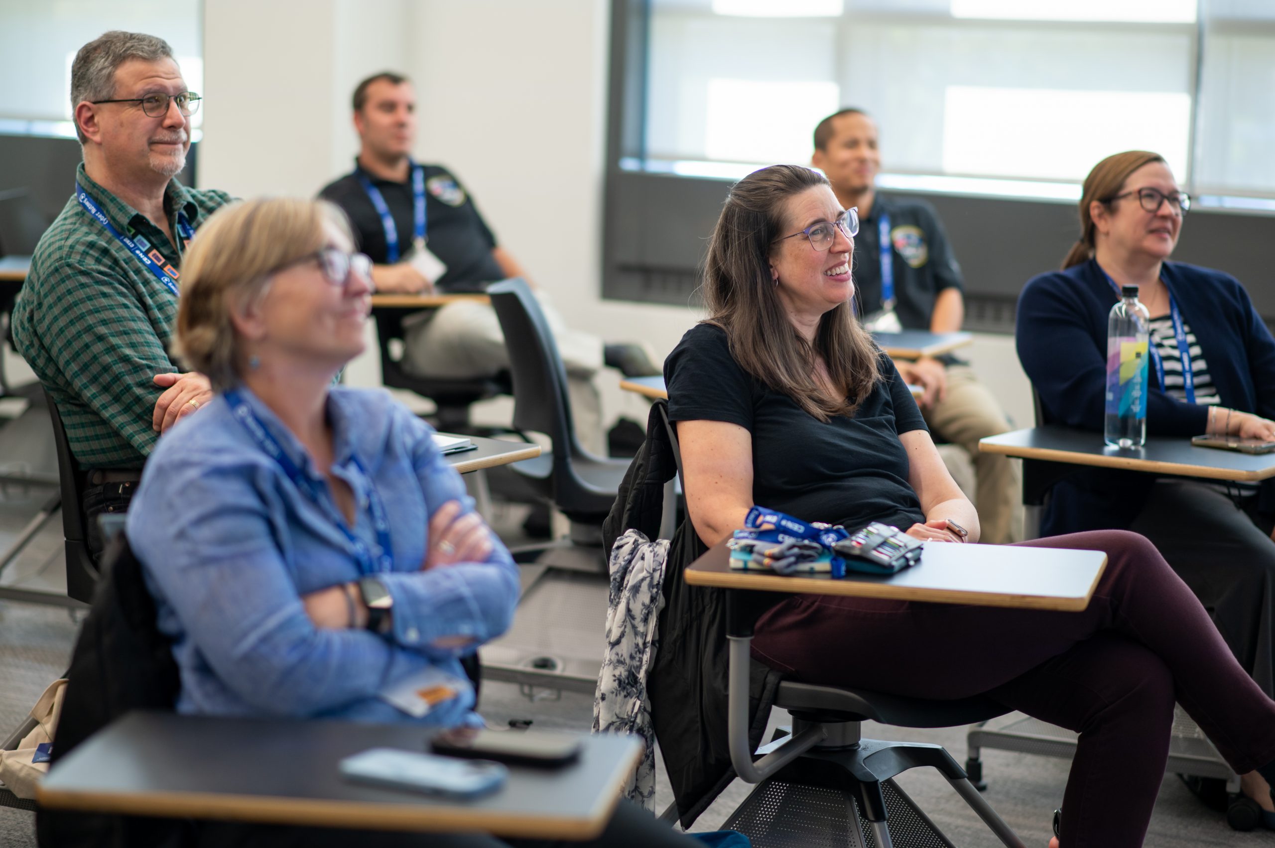 Attendees smiling and listening to a session speaker in a classroom setting