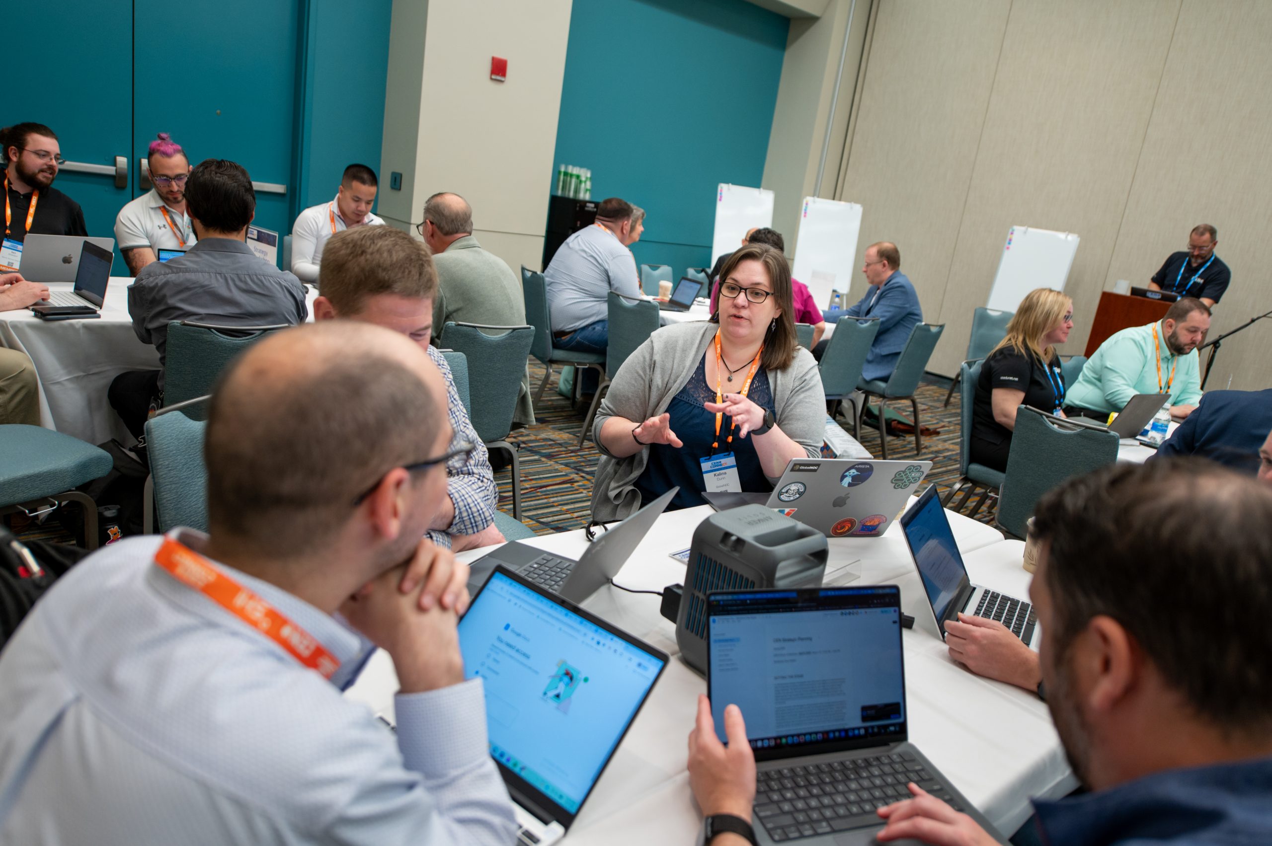 Attendees gathered around a table with their computers talking to eachother